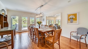A dining area with a wooden table and chairs, a hanging light fixture, and a painting on the wall. - 5 ⭐️ property! Private pool!!SHORT walk to beach!! ❤️ of Sea Pines. Sleeps 12 (Hilton Head Island)