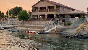 A waterfront property with a large house, a dock, and boats. - RIVERFRONT PARADISE OASIS W/ PRIVATE BEACH & BOAT DOCK (Mohave Valley)
