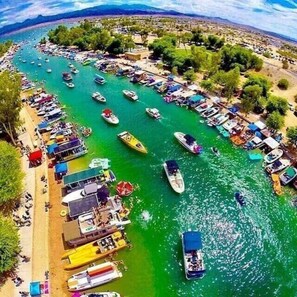 A marina with numerous boats docked along the shore, surrounded by greenery and a clear sky. - RIVERFRONT PARADISE OASIS W/ PRIVATE BEACH & BOAT DOCK (Mohave Valley)