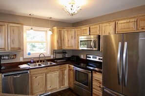 Une cuisine moderne avec des meubles en bois, des appareils électroménagers en acier inoxydable et une fenêtre qui laisse entrer la lumière naturelle.