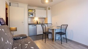 Un espace de vie compact comprenant un canapé, une table à manger, des chaises, un four à micro-ondes et un lave-vaisselle.