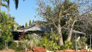A house with a corrugated metal roof, surrounded by tropical plants and large rocks. - Quiet Studio Hideaway 5 minutes Walk to Cable Beach (Cable Beach)