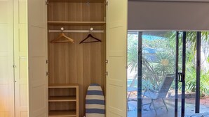 A room with a bed, a patterned rug, a wooden closet with hangers, and a surfboard. - Quiet Studio Hideaway 5 minutes Walk to Cable Beach (Cable Beach)