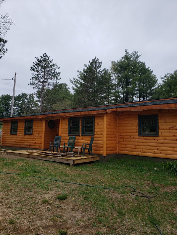 A log cabin with a porch, three windows, and a small deck with chairs. - NEW FAMILY CABIN! WELCOME! (Warrensburg)