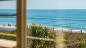 A view of a beach with a wooden fence and palm trees.