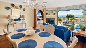 A dining area with a round table, blue placemats, and a chandelier.