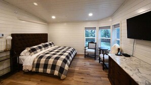Ein Schlafzimmer mit Bett, Sessel, Tisch und Fernseher.