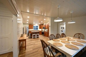 A spacious kitchen with wooden cabinets, a central island, and pendant lighting.