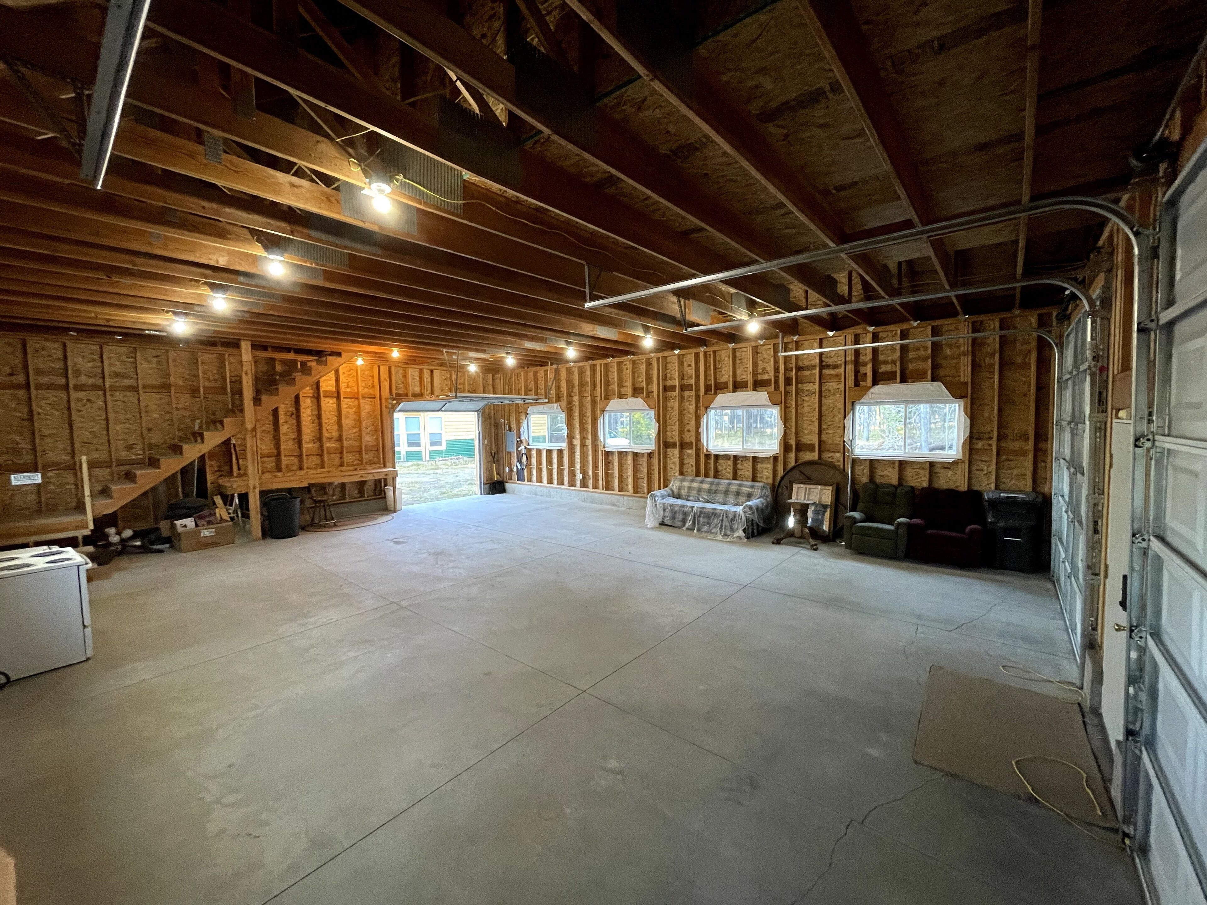 A spacious garage with wooden walls, a concrete floor, and a large open area.
