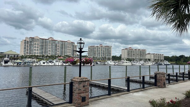 A waterfront view with a marina, docked boats, and a row of hotels in the background. - Amazing Studio, 5 minutes to the Private Beach.  (Myrtle Beach)