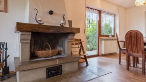A cozy room with a stone fireplace, a wooden dining table, and a chair. - Eifelnatur (Haus 1) by Interhome (Immerath)