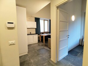 Quarto de hotel compacto com cozinha compacta, área de refeições e porta que dá para outro espaço.