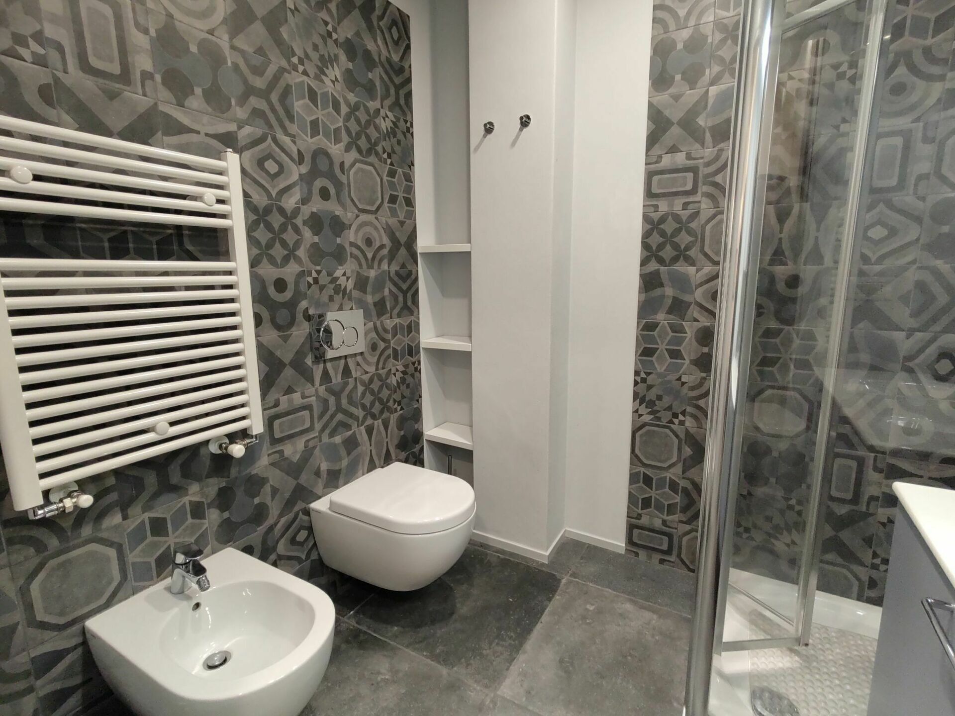 A bathroom with a bidet, toilet, and shower area.