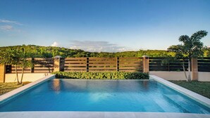 A swimming pool with a wooden fence and greenery in the background. - Carthys Estate (Saint philip)