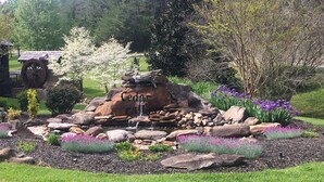A garden with a water feature labeled 'Cedar Falls', surrounded by rocks and various flowering plants. - Papa Bear’s Retreat, Cedar Falls, 2 BD, 3 BA, Queen Bunk Bed in loft, Fireplaces (Sevierville)