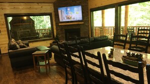 A cozy living room with a fireplace, a television mounted on the wall, and a dining area with a table and chairs. - Papa Bear’s Retreat, Cedar Falls, 2 BD, 3 BA, Queen Bunk Bed in loft, Fireplaces (Sevierville)