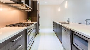 A modern kitchen with a gas stove, stainless steel appliances, and a large island with a sink.