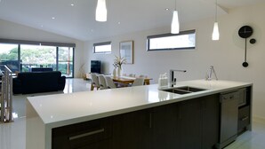 A modern kitchen with a large island, pendant lighting, and a dining area with a sofa and chairs.