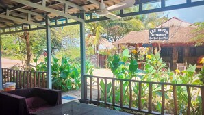 A covered outdoor seating area with wicker furniture and a view of a restaurant named "Lee Huor" in the background. - The Azure - M'Pai Bay (Koh Rong Sanloem)