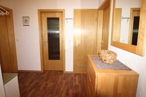 A room with wooden flooring, a wooden bench, a mirror, and a door with a frosted glass panel. - Fewo Schwarzwald 1060m - Ferienwohnung (Todtnauberg)