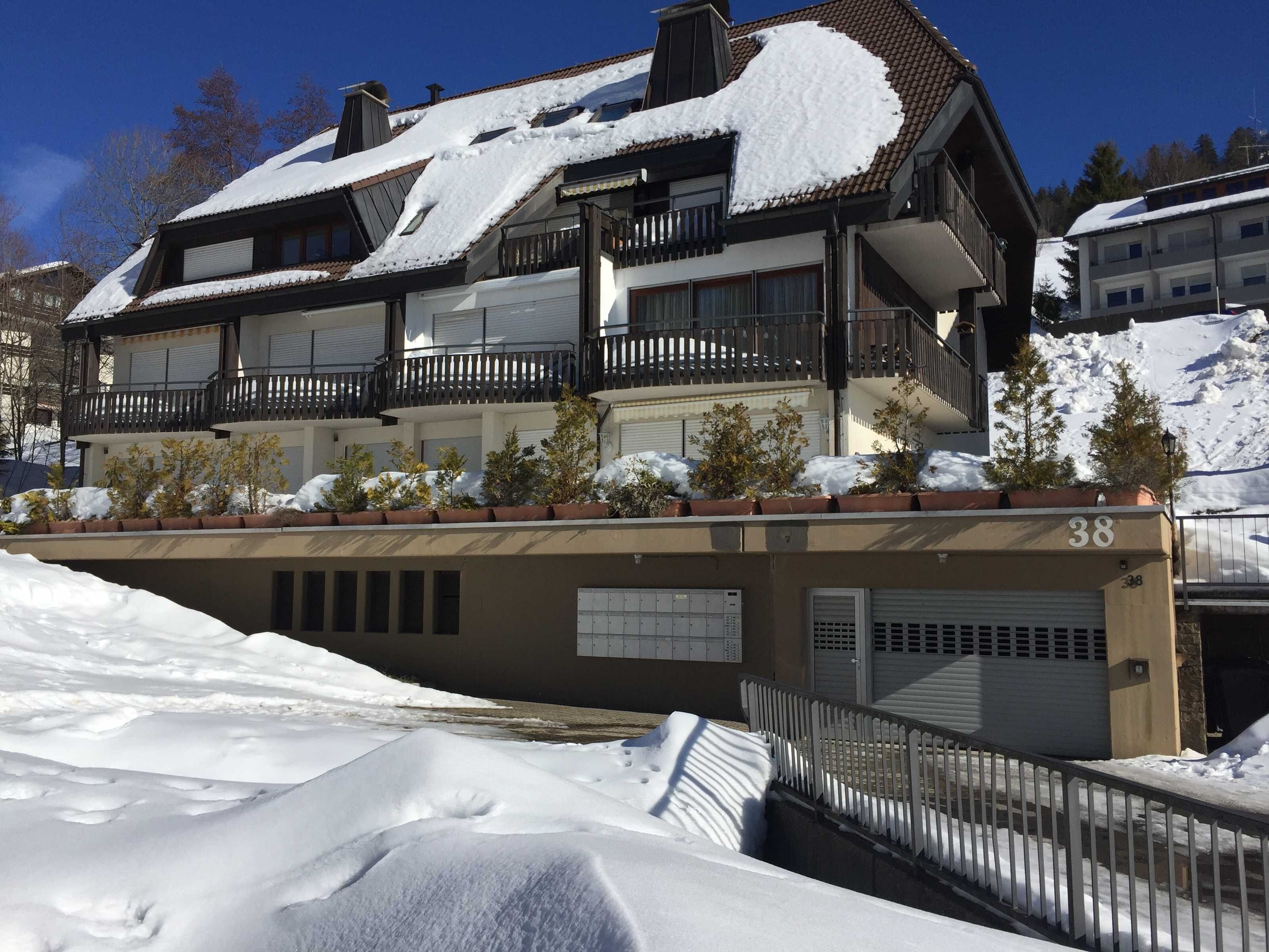 Un edificio de varios pisos con balcones, techo cubierto de nieve y un cartel con el número 38.