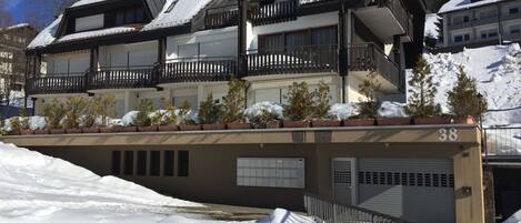 Un edificio de varios pisos con balcones, techo cubierto de nieve y un cartel con el número 38.