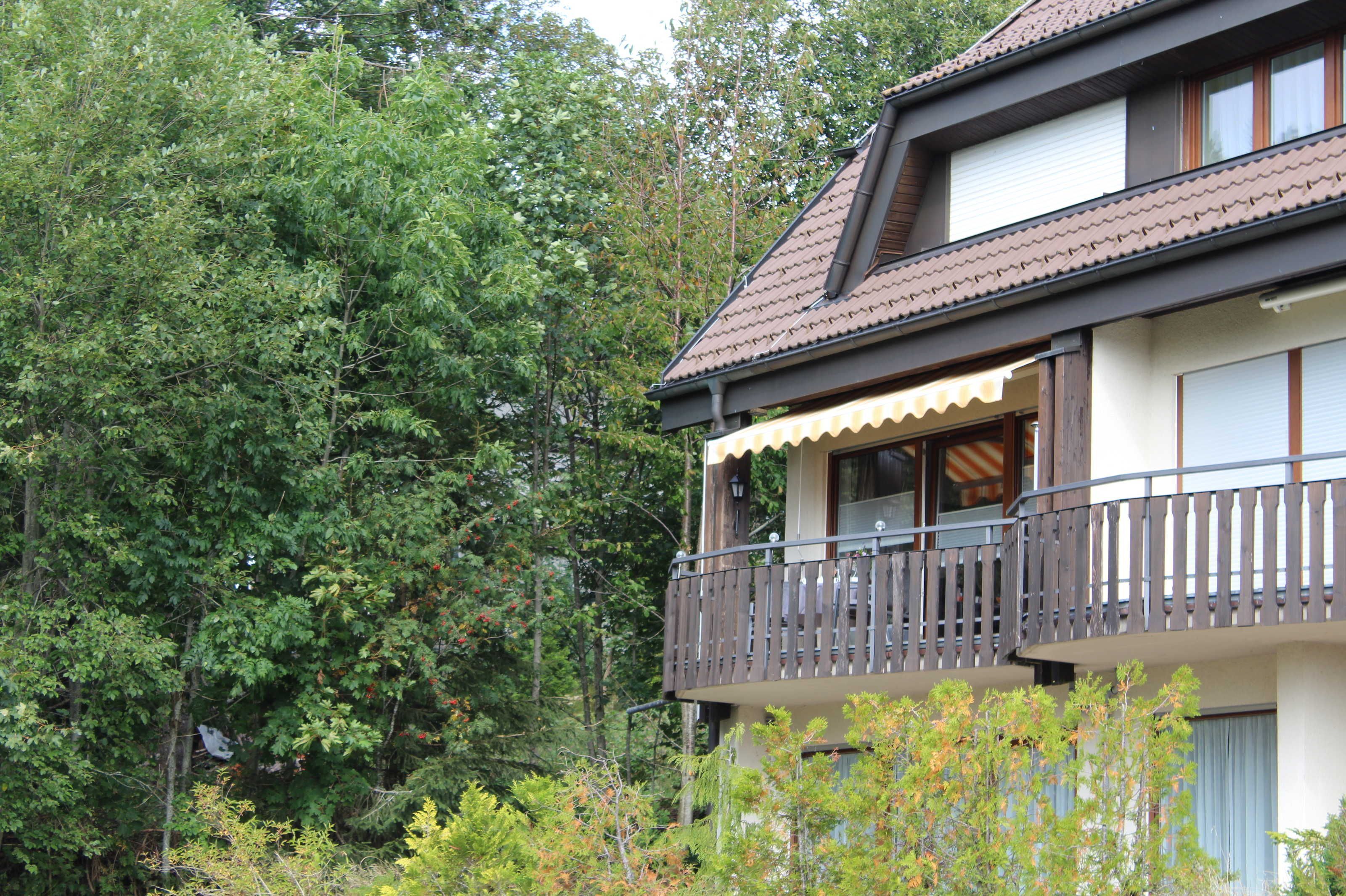 A two-story building with a balcony, surrounded by dense trees.