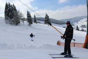A ski slope with snow-covered trees and a person standing with ski poles. - Fewo Schwarzwald 1060m - Ferienwohnung (Todtnauberg)