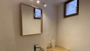 A bathroom with a wooden vanity, a large mirror, a modern sink, and a window.