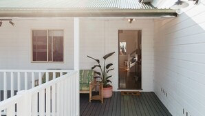A covered porch with a white railing, a potted plant, and a wooden bench. - Anchor in Avoca Beach - enjoy your 4 bedroom coastal getaway (Avoca Beach)