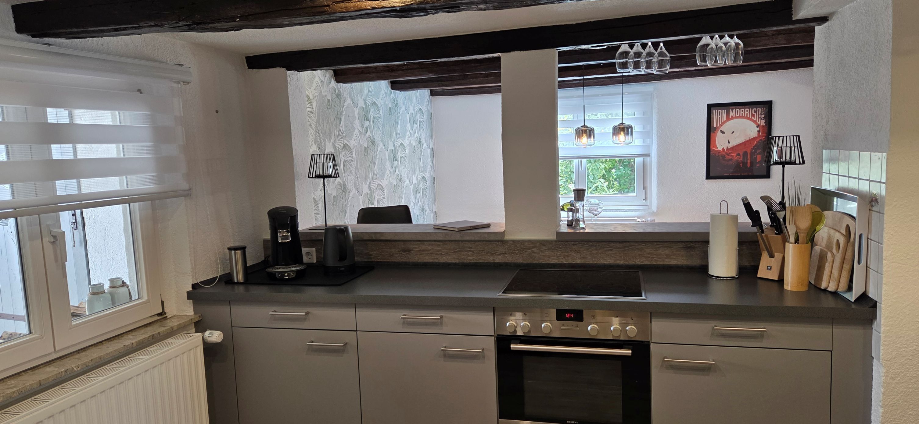 A kitchen with a built-in oven, a coffee maker, and a window with a view of greenery.
