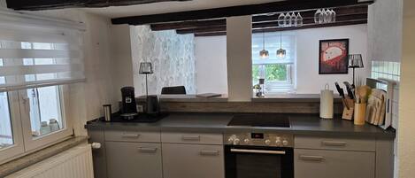 A kitchen with a built-in oven, a coffee maker, and a window with a view of greenery.