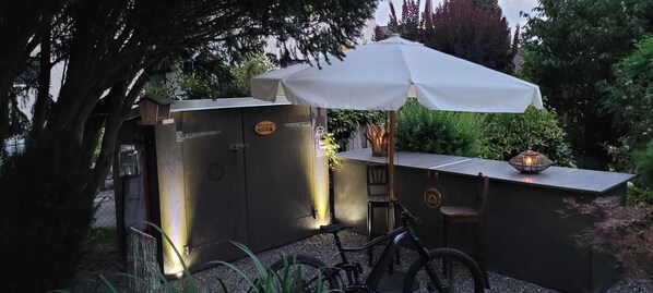 A rustic outdoor seating area with a table, chairs, and a bicycle.