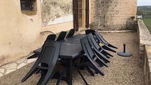 Ein Essbereich im Freien mit Tisch und Stühlen, eine rustikale Steinmauer und eine Tür.
