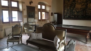 Ein Zimmer mit einem großen Gemälde, einer Couch, zwei Sesseln, einem Tisch und einem Kamin.