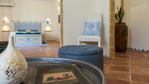 A room with a bed, a chair, a decorative vase, and a wall-mounted mirror.