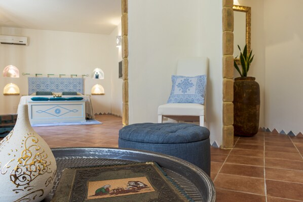 A room with a bed, a chair, a decorative vase, and a wall-mounted air conditioner.