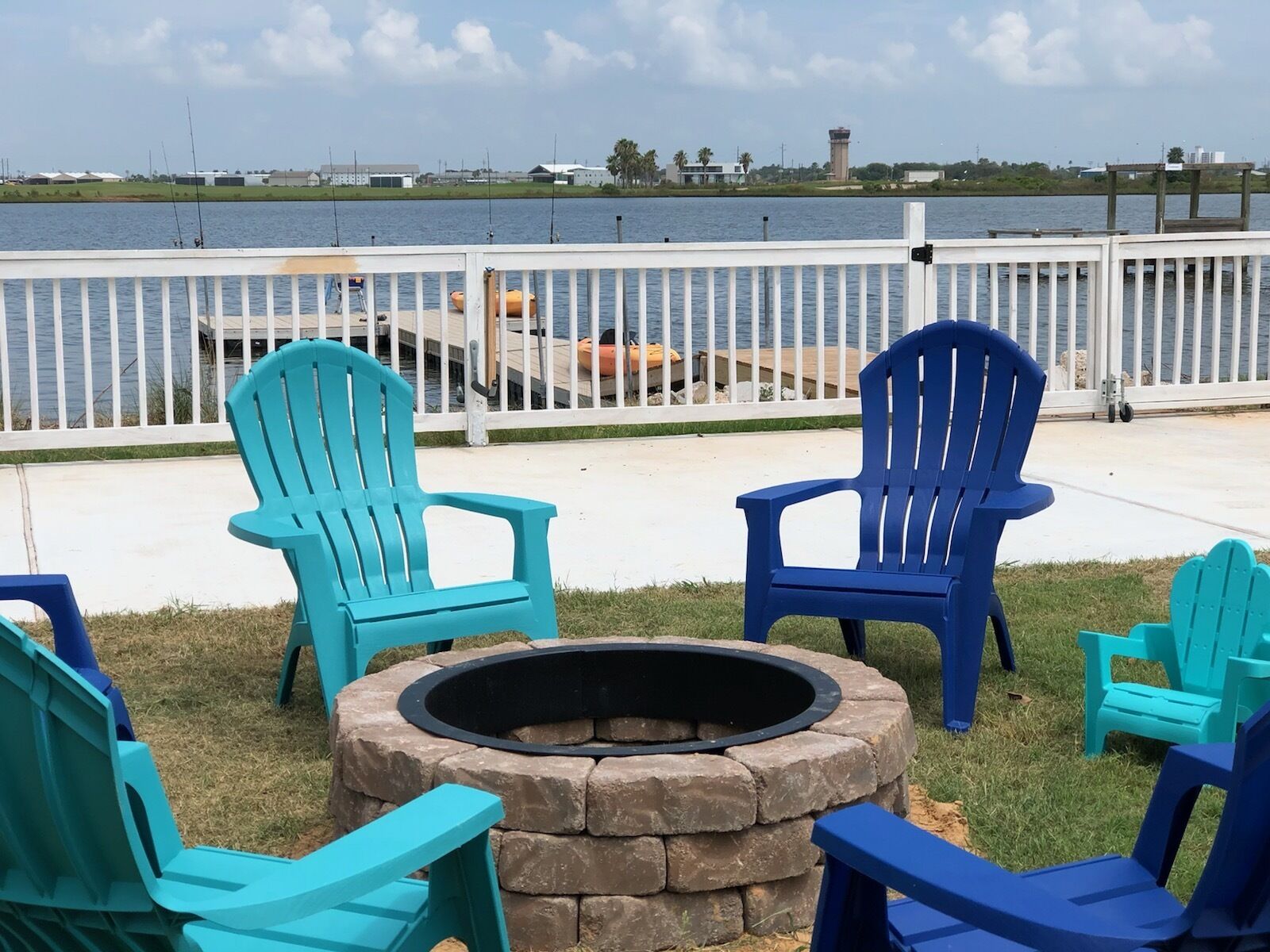 A lakeside seating area with Adirondack chairs and a stone fire pit.