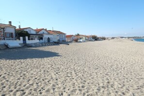 A sandy beach with white buildings with red roofs in the background.