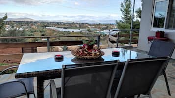 En terrasse med et bord dækket til to, der kigger ud over et smukt landskab med bjerge og vand.