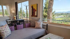 Une chambre confortable avec un lit, une petite table et une vue sur un paysage verdoyant.