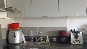 Een compacte keuken met een ingebouwde oven, een vaatwasser en een koffiezetapparaat.