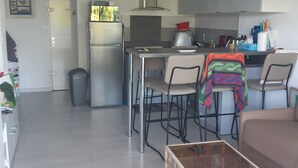 Een moderne keuken met roestvrijstalen apparatuur, een eethoek met een tafel en stoelen, en een woonkamer met een bank en salontafel.