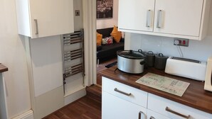 A kitchen with white cabinets, a wooden countertop, a slow cooker, a toaster, and a coffee maker. - South Shield's Hidden Gem Garnet 3 Bedroom Apartme (South Shields)