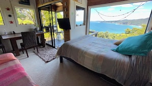 Ein Schlafzimmer mit einem großen Bett, einem Schreibtisch und Blick aufs Meer.