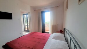 Une chambre à coucher avec un lit, une fenêtre et une porte donnant sur un balcon.