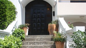 Un bâtiment blanc avec une porte noire, le numéro 33, et un escalier menant à l’entrée.