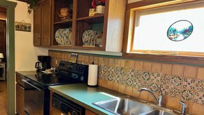 A kitchen with wooden cabinets, a stainless steel sink, and a tiled backsplash.