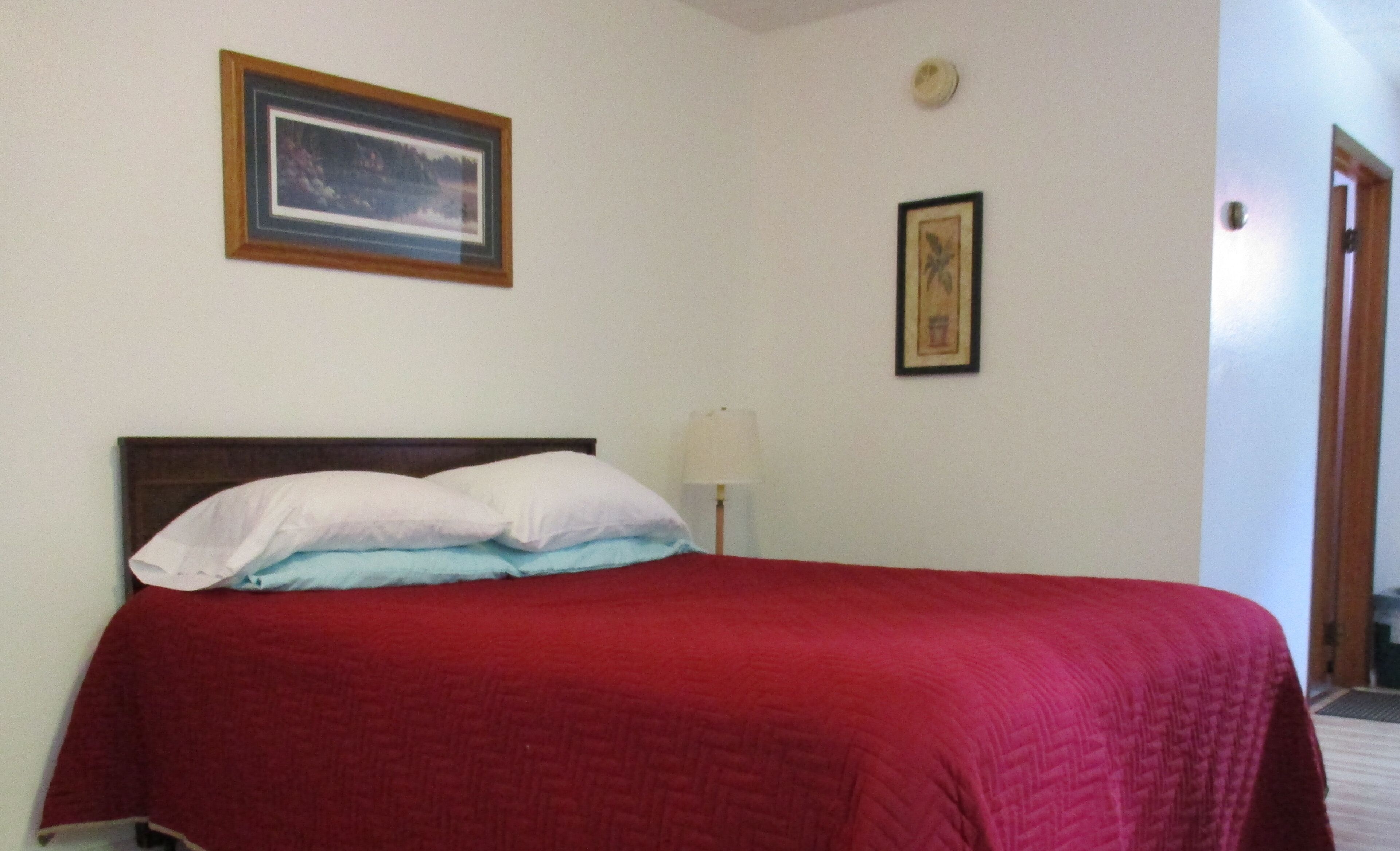 A room with a bed, a framed picture on the wall, and a door.