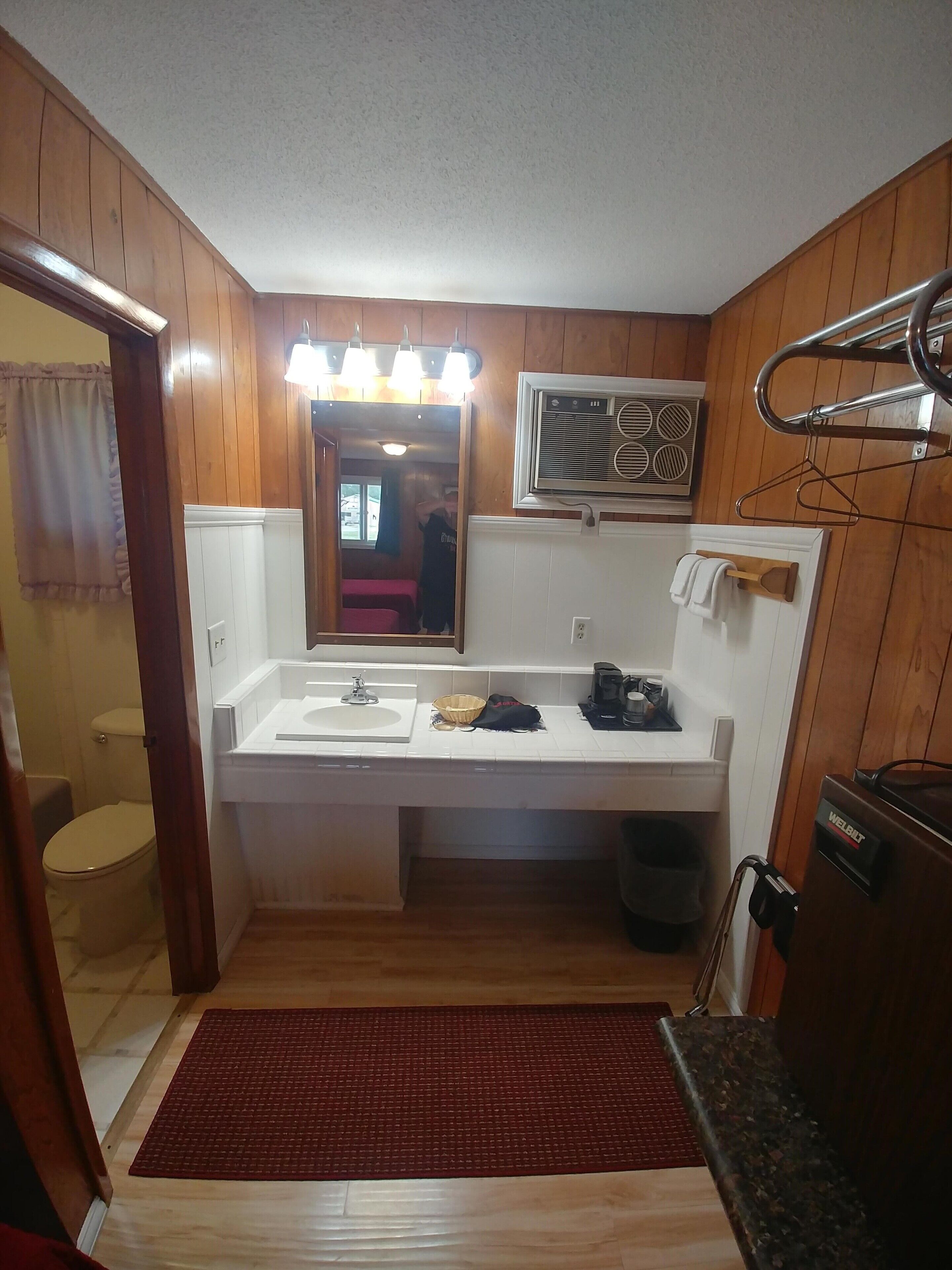 A compact bathroom with a wooden interior, a sink, a mirror, and a towel rack.